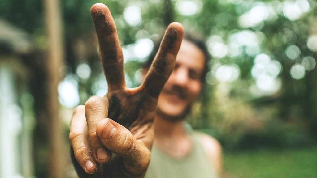 Guy at music festival with dirty hands making a peace sign with his fingers